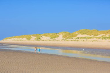 Tropik plajda oynayan çocuklar. Su sıçratma eğlencesi. Deniz dalgalarında süzülen küçük çocuk. Çocuklar yaz tatilinde yüzer ve oynarlar. Kum ve su oyuncağı, küçük çocuklar için güneş koruması.. 