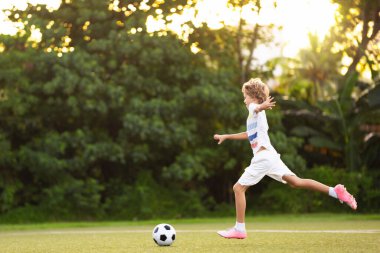 Çocuk futbol oynuyor. Çocuklar dışarıda futbol oynarlar. Küçük çocuk yaz parkında topa vuruyor. Küçük çocuklar için sağlıklı bir aktivite. Okul spor kulübü takımı. Futbol Küçükler Ligi.