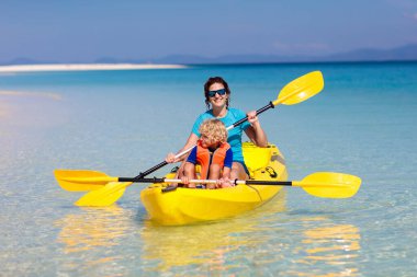 Çocuklar okyanusta kayak yapıyor. Tropikal denizde kanodaki çocuklar. Genç bir çocukla aktif tatil. Ebeveynler, küçük bir oğlan ve güzel bir sahilde kanodaki bir kız. Çocukla birlikte tatil aktivitesi. Aile suyu eğlencesi.