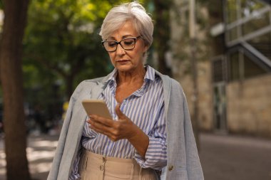 Açık havada akıllı telefon kullanan son sınıf öğrencisi.