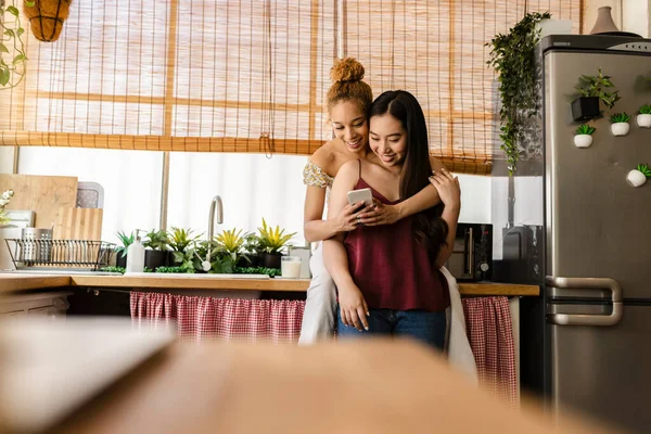 Pareja Lesbiana Multirracial Abrazándose Cocina Viendo Las Redes Sociales Teléfono — Foto de Stock