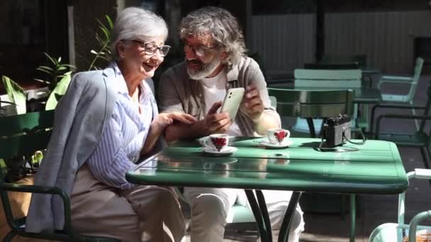 上了年纪的夫妻坐在阳台上 一边看着智能手机上的社交网络 一边喝咖啡 — 图库视频影像