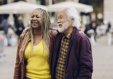 Çok ırklı üst düzey bir çift şehirde yürüyüş yaparken eğleniyor. Asyalı adamın yüzüne odaklan.