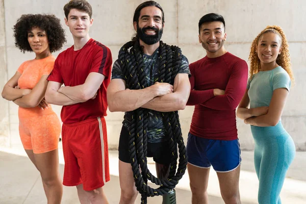 stock image Man with orthopedic leg and battle rope hanging around the neck. Multiracial athletes with arms folded.