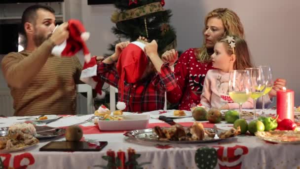 Szczęśliwa Biała Rodzina Kapeluszami Mikołaja Śmiejąca Się Obchodząca Świąteczną Kolację — Wideo stockowe