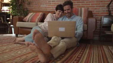 A middle-aged married couple is relaxing in the living room at home barefoot on the floor