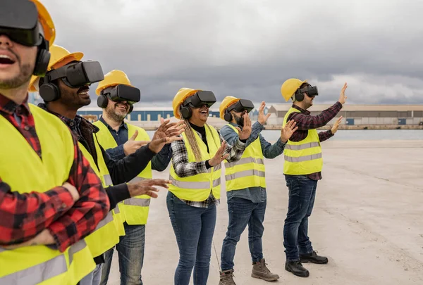 Multiracial group of workers in reflective vests and helmets with virtual reality goggles directing the transport of goods in the outdoors