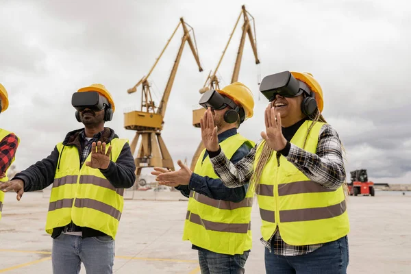 Three of workers in reflective vests and helmets with virtual reality goggles