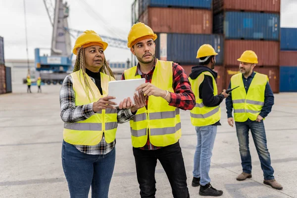 Multiracial group of workers in reflective vests directing the transport of goods in the outdoors