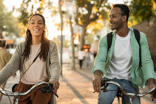 stock image Close up african american couple riding in the city. Happy young students cycling at sunset