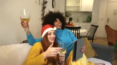 Çok ırklı bayan arkadaşlar Noel 'i kutluyorlar. Video çağrısı ve alkol ile içki.