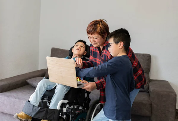 Latin family using laptop for watching a video. Hispanic family with two sons and single mother. Paraplegic boy in a wheelchair. Focus on woman face