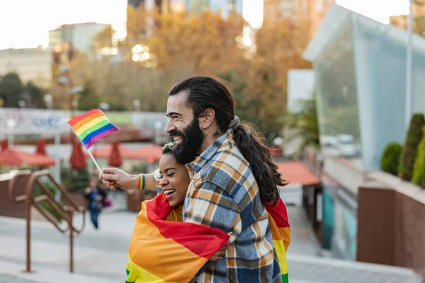 Diverse people walking in the Pride parade with the rainbow flag as a symbol of Pride month. couple of diverse friends walk happily with lgbt flags
