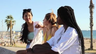 female friends in summer clothes eating ice cream on the street