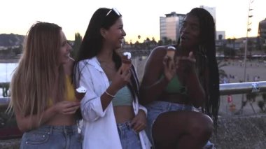 multiracial female friends ready to go to the beach are sitting talking and laughing