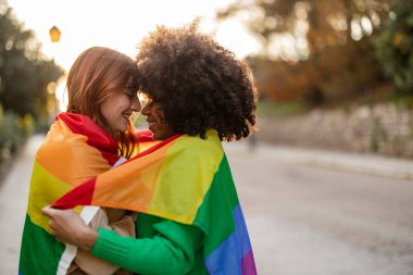 two multiracial women together lgbt flag - focus on redhead woman -