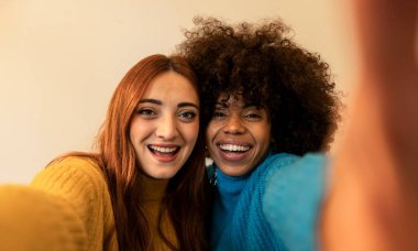 selfie of two happy multiracial women lesbian couple at home.