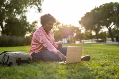 student woman in university campus break laptop and food - african american curvy woman eating a sandwich