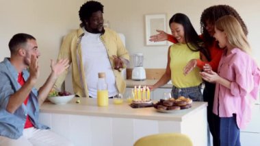 Bir doğum günü partisinde kutlama yapan bir grup çok ırklı neşeli arkadaş. Arkadaşlar parti sırasında doğum günü pastasıyla doğum günü kızına tezahürat edip sürpriz yapıyorlar.