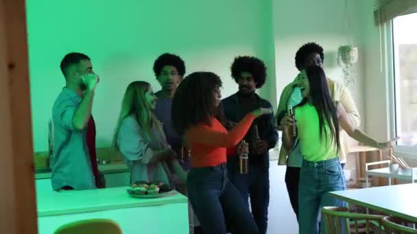 パーティーを祝うためにアルコールビールを提供しながら キッチンに集められた腕を上げた多人種間の友人のグループ — ストック動画