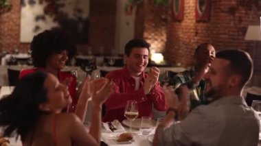 group of friends gathered at dinner in restaurant applaud - multiracial friends at dinner applauding and smiling on terrace