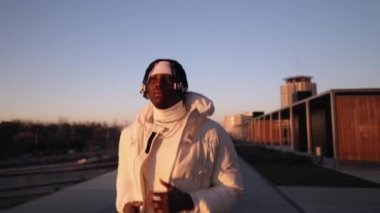 african man walks at sunset in financial area with buildings