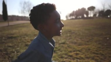 handsome african american boy running in the park sunny day