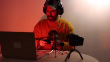 pro gamer blogger shooting vlog while playing video game at home late at night. Young cyber sportsman streaming his gaming, taking part in online tournamen