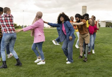 large group of diverse friends having fun together dancing in the park