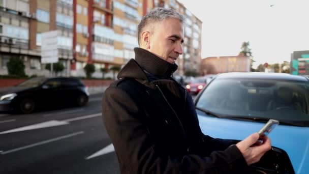 Dojrzały Mężczyzna Siwymi Włosami Ładuje Swój Elektryczny Samochód Mieście — Wideo stockowe
