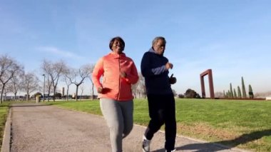 Güneşli bir günde parkta koşan son sınıf çifti kendilerine bakmak için spor yapan bir çift tombul insan, kıvrımlı kadın, Afrikalı Amerikalılar..