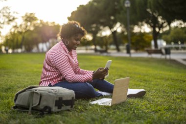 Kavisli bir kadın, çim bilgisayarlı bir çanta akıllı bir telefon üniversite kampüsünde tombul bir kız öğrenci.
