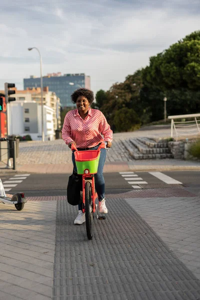 curvy young woman in modern city electric e-bike clean sustainable urban transport, happy african american backpacker traveling.