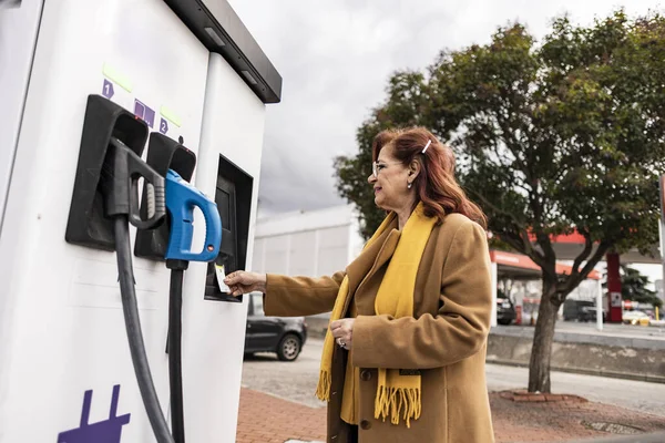 mature woman charging car at charging point