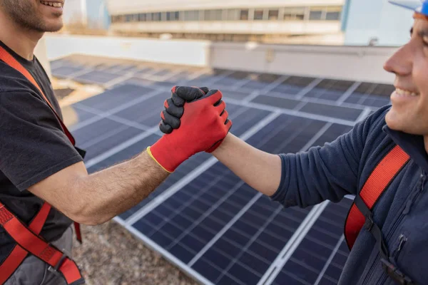 workers shake hands solar panels