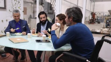 Farklı yaşlardaki iş arkadaşları ofiste birlikte öğle yemeğinin tadını çıkararak sosyal içeriği ve toplum bilincini teşvik ediyorlar.