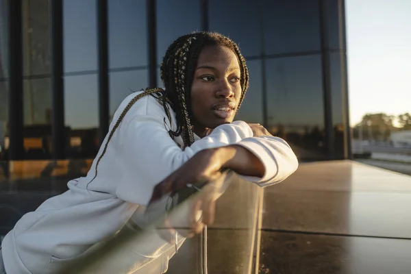 stock image Silhouetted against a backdrop of city skyscrapers and the warm glow of a setting sun, the pretty African American woman radiated confidence and beauty