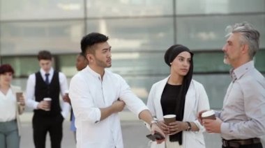 co-workers of different ages smiling as they leave the office - business concept -