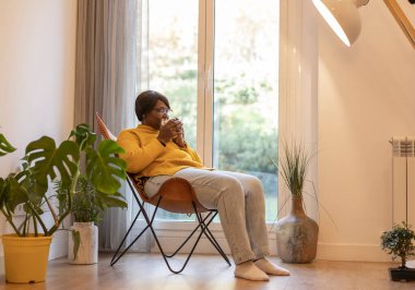 Evde son sınıf öğrencisi bir fincan sıcak içecek içiyor.