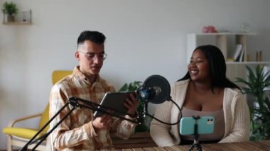 Happy Podcaster 'lar stüdyodaki bir ses yayınında harika bir konuşma yapıyorlar. Neşeli, kıvrımlı İspanyol kadın ve beyaz adam sosyal medya kanalları için internet yayını yapıyor..