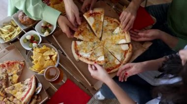 Bar bahçesinde yemek yiyen, restoran masasında oturan mutlu gençlerden oluşan bir grup çok ırklı arkadaş. Herkes kendi payına düşen pizzayı alıyor. -