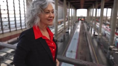 Gri saçlı yaşlı kadın istasyonda dolaşıyor, olgun iş kadınlarını geziyor..