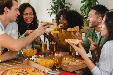 Mutlu çok ırklı arkadaşlar evde birlikte pizza yiyorlar. Mutlu arkadaşlar yemeği, yemek servisi. Gençler içeride yemek yiyor..