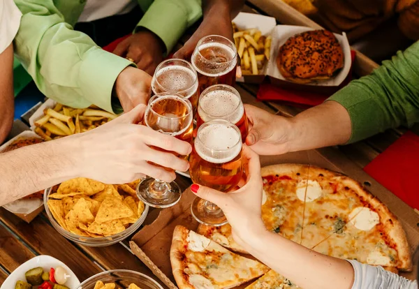 Friends with beer glasses at wooden table with delicious food - Top view having dinner toasting restaurant - Food and drink lifestyle concept -