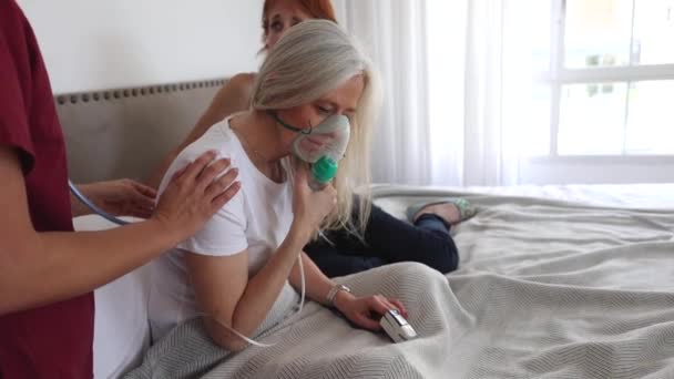 看護師や家族と一緒に座って酸素マスクとベッドの中で美しい先輩女性の肖像画 完全に病気の後に回復 救急車のプレスシニア女性 — ストック動画