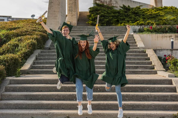 fellow college graduates on the college campus, jump with excitement