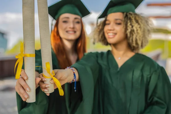 stock image two recent college women graduated with diploma - focus on diplomas -