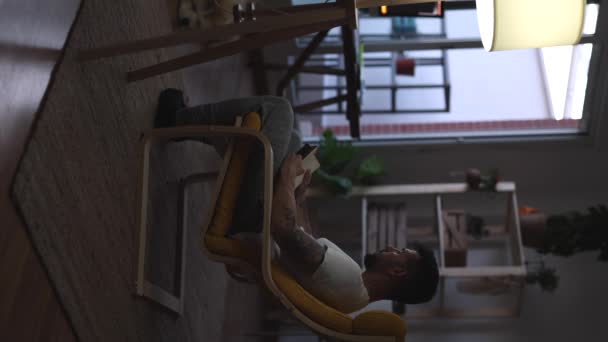 Mann Liest Hause Sessel Bei Gedämpftem Licht — Stockvideo