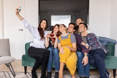 Bir grup beyaz arkadaş modern pansiyonun oturma odasında selfie çekiyorlar.