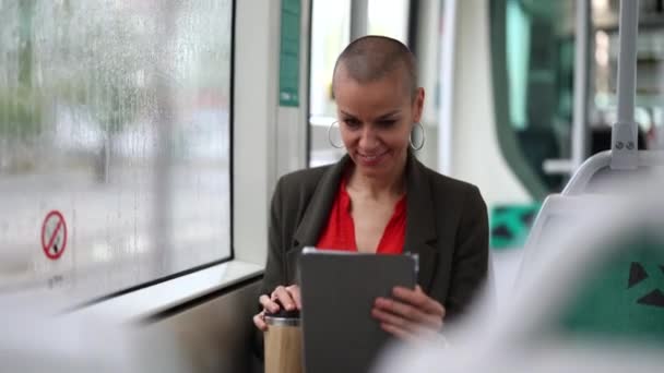 成熟的女商人 光着头 坐在电车里用平板电脑 外面下着雨 她从窗户往外看 — 图库视频影像